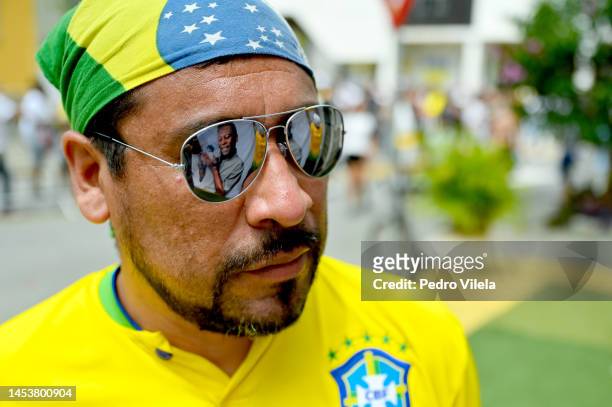 An image of Pelé is reflected on the glasses of a man visiting late football legend Pelé funeral at Vila Belmiro stadium on January 02, 2023 in...