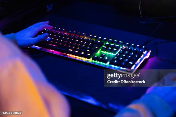 hand next to rgb illuminated gaming keyboard, in gamer's dark room. keyboard concept, lights, colorful, glowing, mechanical keyboard and computer gaming. - instrumento musical de tecla imagens e fotografias de stock