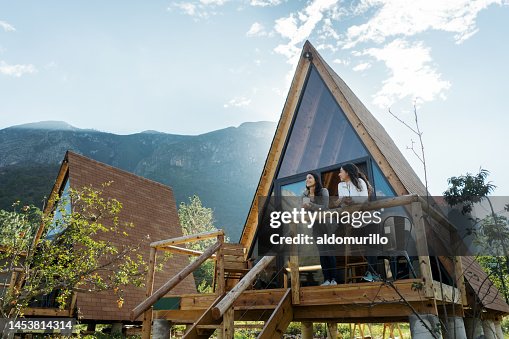 Two female friends enjoying hot drink outside of cabin