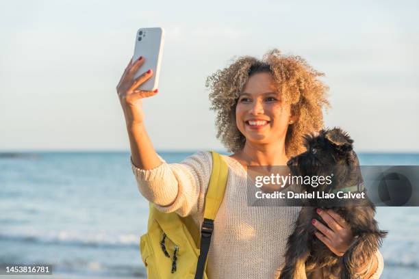 afro descendent woman taking selfie on beach with dog next to them - de ascendencia europea 個照片及圖片檔