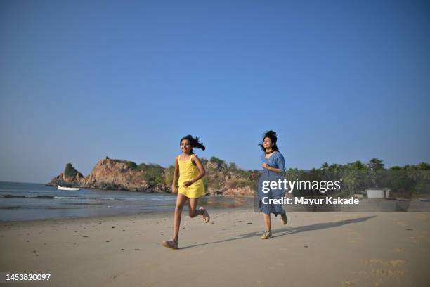 mother and daughter running on the beach - indian mother and child stock pictures, royalty-free photos & images