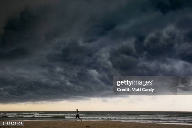 Man walks as dark stormy rain clouds gather in the sky above the sea and beach on January 27, 2010 in Accra, Ghana. Located on the southern coast at...