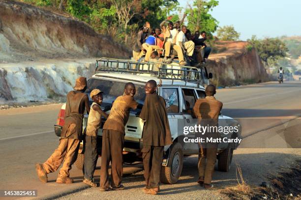 People push a broken down old and battered Peugeot 505 estate car towards the Mali and Guinea frontier and border on January 24, 2010 in Kouremale,...