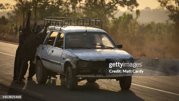 People push a broken down old and battered Peugeot 505 estate car towards the Mali and Guinea frontier and border on January 24, 2010 in Kouremale,...