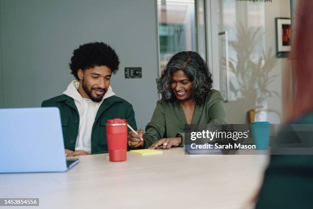 male and female colleague in meeting writing notes - sarah green stock pictures, royalty-free photos & images