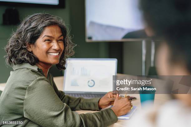 female colleague chatting to coworker - boss over shoulder stock-fotos und bilder