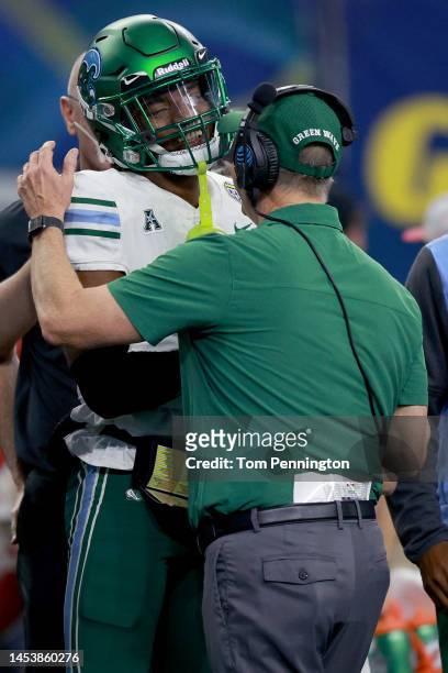 Deuce Watts of the Tulane Green Wave laughs with head coach Willie Fritz of the Tulane Green Wave while being helped off the field after a play...