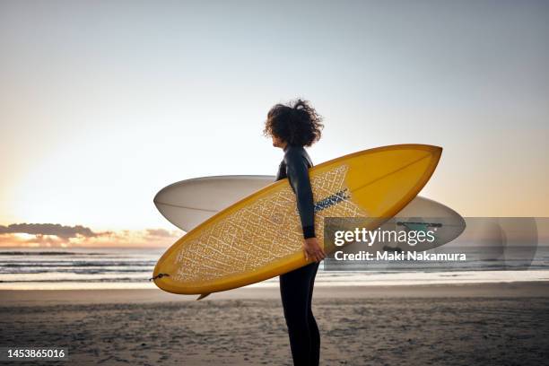 woman with surfboard under her arm at the beach. - surfbrett stock-fotos und bilder
