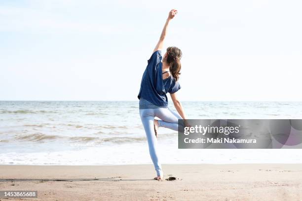 a woman doing yoga on the beach. - beach yoga stock-fotos und bilder