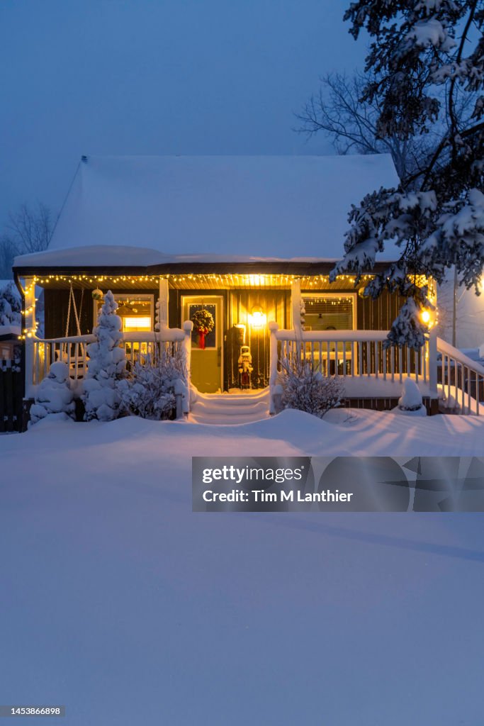 Quaint snowy house at night decorated for Christmas. Fresh snow on the ground.