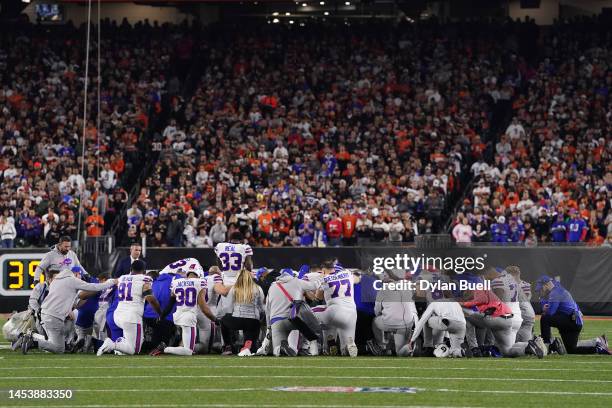 Buffalo Bills players huddle and pray after teammate Damar Hamlin collapsed on the field after making a tackle against the Cincinnati Bengals during...
