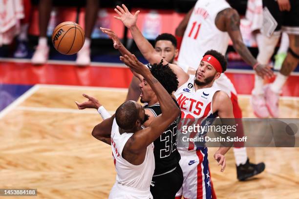Tre Jones of the San Antonio Spurs passes the ball while guarded by Seth Curry and Kevin Durant of the Brooklyn Nets during the third quarter of the...