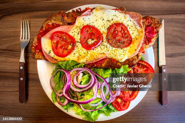 milanesa napolitana (neapolitan milanese) with lettuce, tomato and onion salad. typical and traditional argentine food. - milanese 個照片及圖片檔