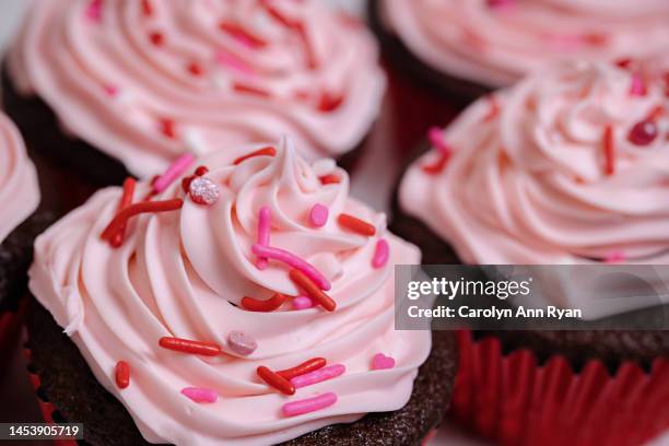 close-up of chocolate cupcake with pink frosting and red sprinkles - fondant stock pictures, royalty-free photos & images