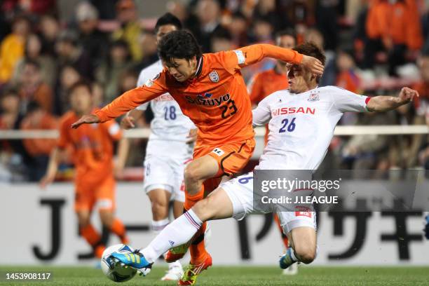 Ryohei Shirasaki of Shimizu S-Pulse is tackled by Naoaki Aoyama of Yokohama F.Marinos during the J.League Yamazaki Nabisco Cup Group B match between...