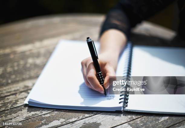 young woman writing in spiral notebook at outdoor table - caneta esferográfica imagens e fotografias de stock