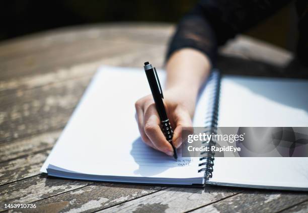 young woman writing in spiral notebook at outdoor table - ballpoint pen 個照片及圖片檔