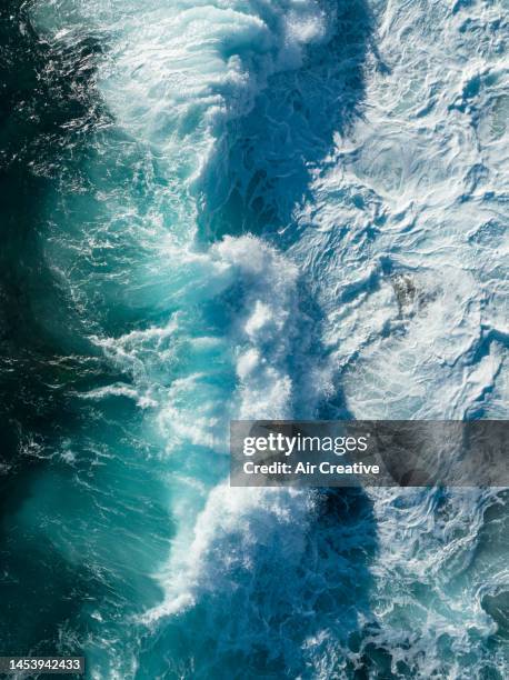 top-down aerial view of waves breaking on the coastline during a strong wind day - vista marina fotografías e imágenes de stock