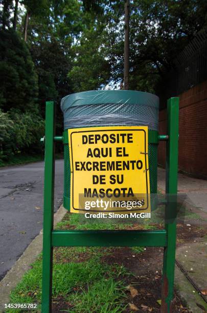 curbside trash bin with a spanish-language sign stating 'deposite aqui el excremento de su mascota, gracias' [deposit your pet's excrement here, thank you] - dog waste bin stock pictures, royalty-free photos & images