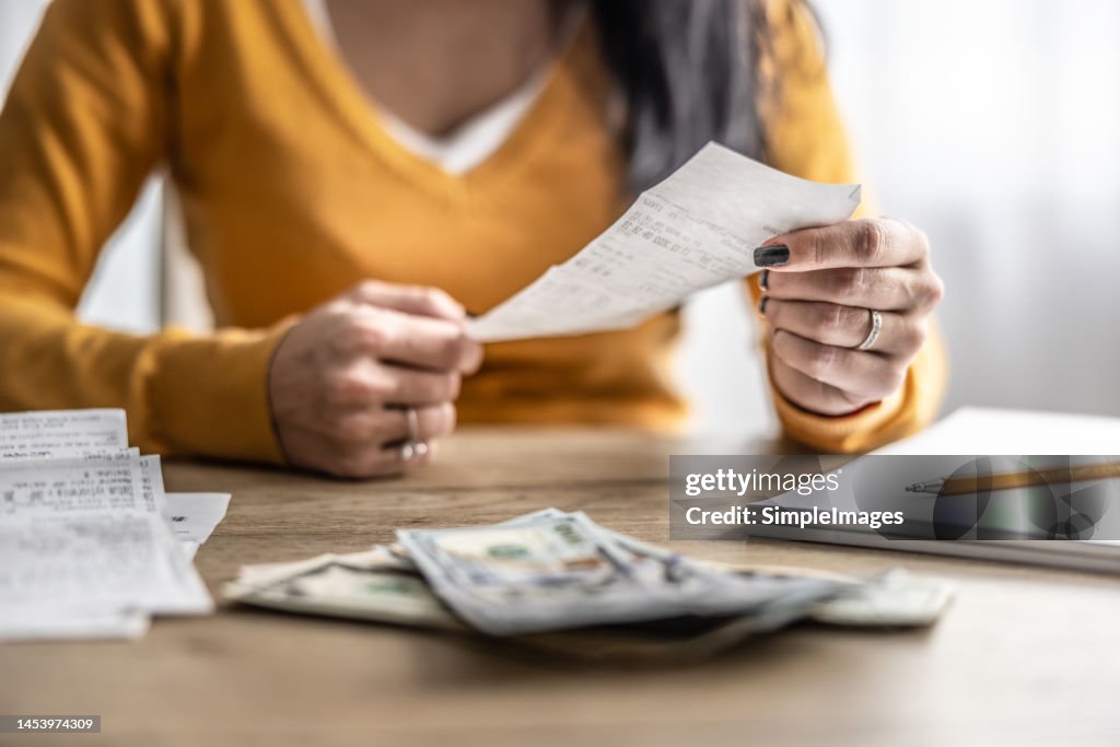 Close-up of the hands of a young woman checking shopping receipts.