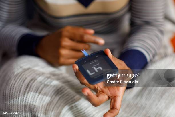 young woman checks her glucose level at home - hypoglycemia stock pictures, royalty-free photos & images