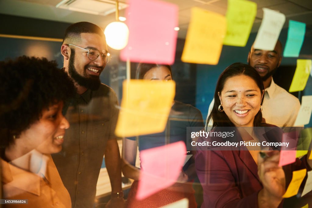 Diverse businesspeople smiling while having a brainstorming session using adhesive notes