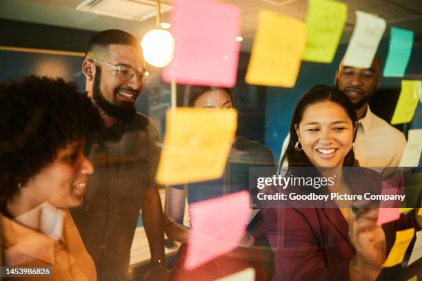 diverse businesspeople smiling while having a brainstorming session using adhesive notes - sharing ideas stock pictures, royalty-free photos & images