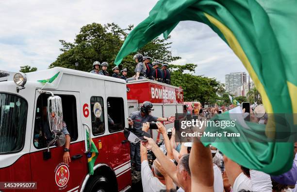 Fan waves a Brazilian flag as the coffin of Brazilian football legend Pelé is transported atop a fire truck in a funeral procession through the...
