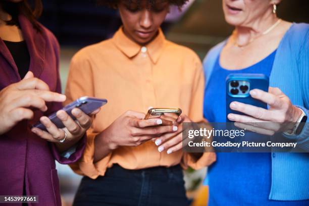 diverse businesswomen standing with their phones during an office break - partilha de ficheiros imagens e fotografias de stock