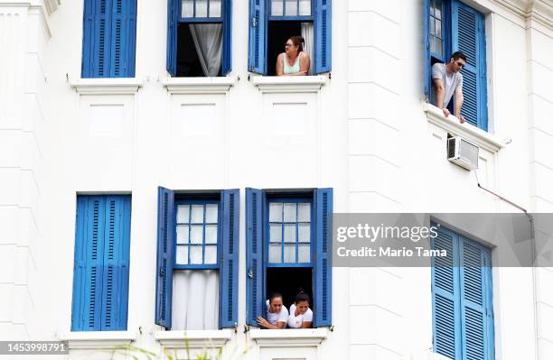 People watch from windows as the coffin of Brazilian football legend Pelé is transported in a funeral procession through the streets of Santos on the...