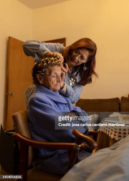 mature woman combing her old mother's hair - house insulation not posing stock pictures, royalty-free photos & images