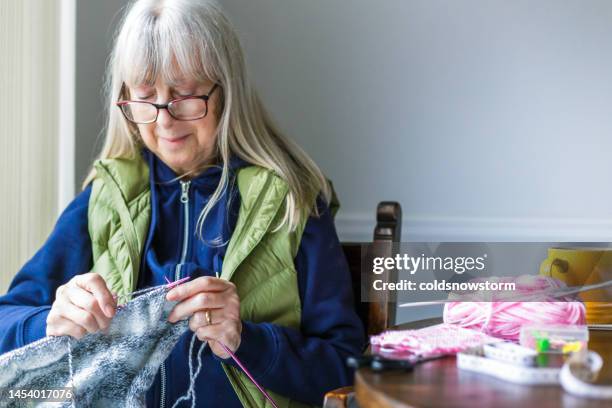 senior woman knitting at home on rainy day - stitch stock pictures, royalty-free photos & images