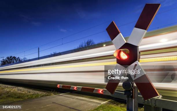 railroad crossing with fast train at blue hour - level crossing stock pictures, royalty-free photos & images