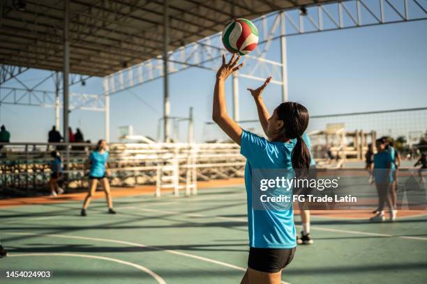 female volleyball player hitting the ball during warm-up at sports court - candid volleyball stock pictures, royalty-free photos & images