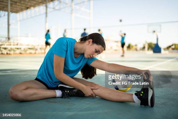 female volleyball player stretching at the volleyball court - leg stretch girl stock pictures, royalty-free photos & images