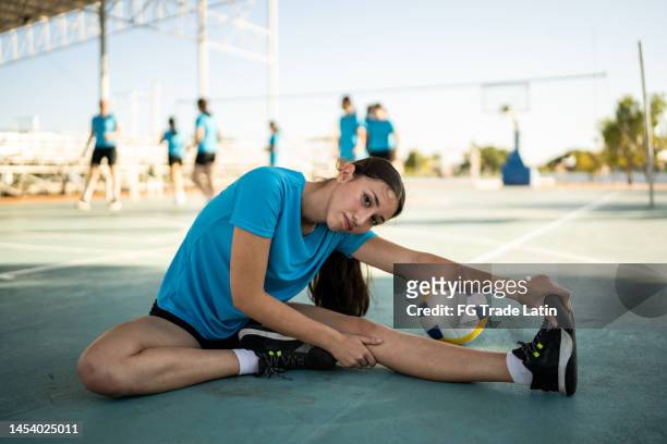 portrait of young woman volleyball player stretching at the volleyball court - leg stretch girl stock pictures, royalty-free photos & images