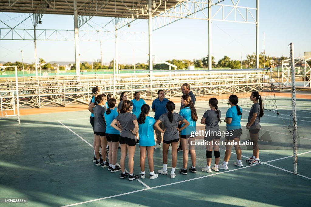 Squadre di pallavolo femminile che ascoltano i loro allenatori prima della partita
