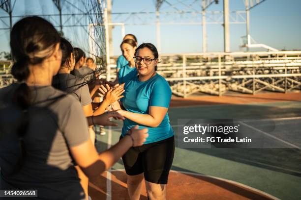 volleyballspielerinnen begrüßen sich vor dem spiel auf dem sportplatz - girl in gym stock-fotos und bilder