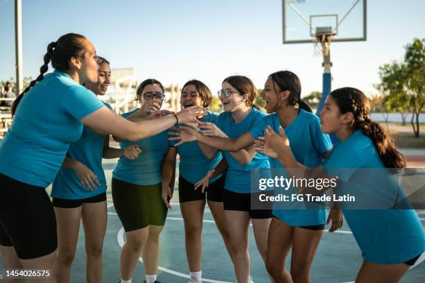 female volleyball team stacking hands while celebrating after the game at sports courts - kids winning stock pictures, royalty-free photos & images