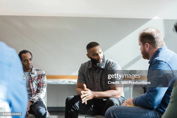 two men have a disagreement during group therapy - addiction recovery stock pictures, royalty-free photos & images