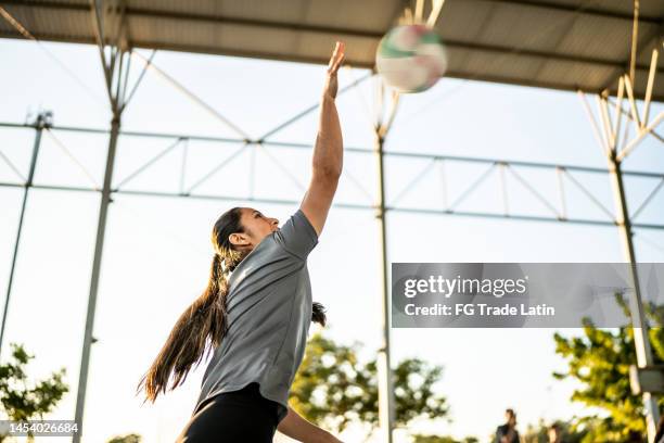 female volleyball player serving the ball during game at sports court - volleyball park stock pictures, royalty-free photos & images