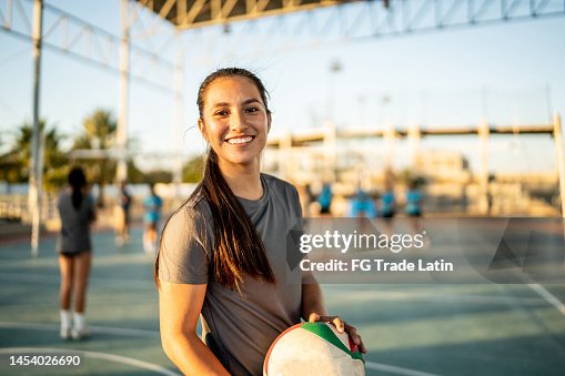 Portrait of female volleyball player holding a volleyball ball at sports court