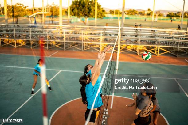 female volleyball players blocking the ball on net during game at sports court - volleyball park stockfoto's en -beelden