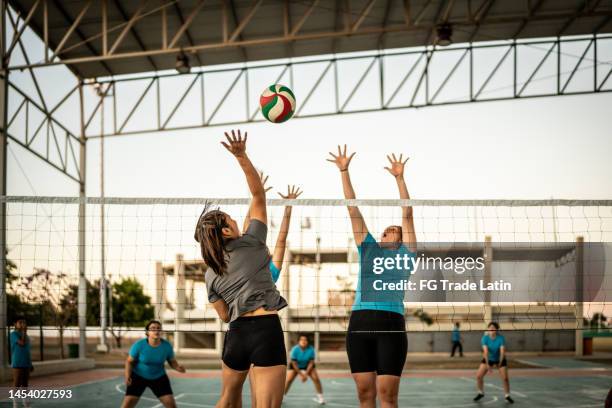jugadora de voleibol golpeando la pelota durante el juego en la cancha deportiva - volear fotografías e imágenes de stock