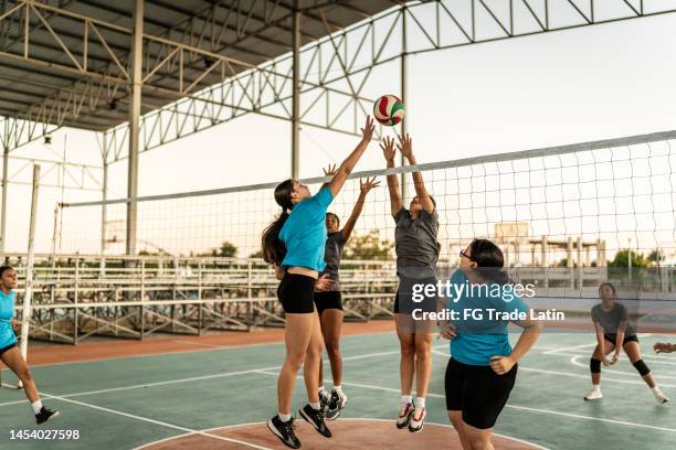 volleyballspielerin spitzt den ball während des spiels auf dem sportplatz - verteidigungsspieler stock-fotos und bilder