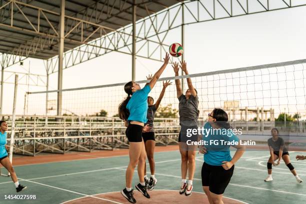 volleyballspielerin spitzt den ball während des spiels auf dem sportplatz - offense sporting position stock-fotos und bilder