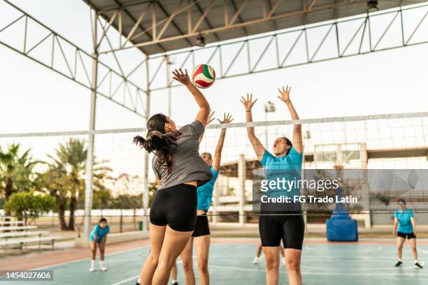 volleyballspielerin spitzt den ball während des spiels auf dem sportplatz - volleyball netz stock-fotos und bilder
