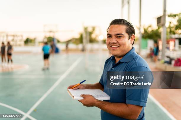 portrait of young coach man holding a note pad at sports court - sports centre exterior stock pictures, royalty-free photos & images