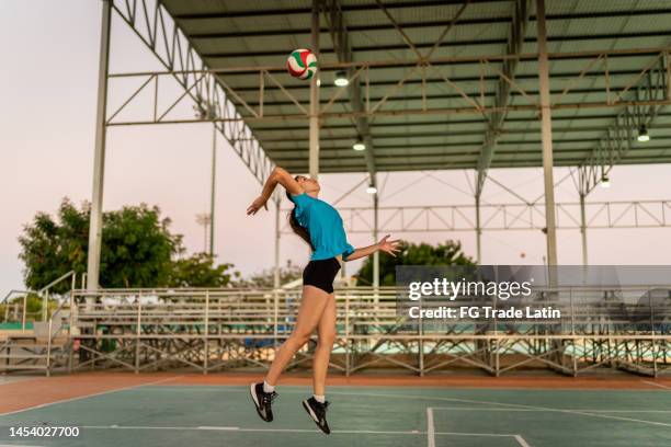 female volleyball player serving the ball during game at sports court - volleyball park stockfoto's en -beelden