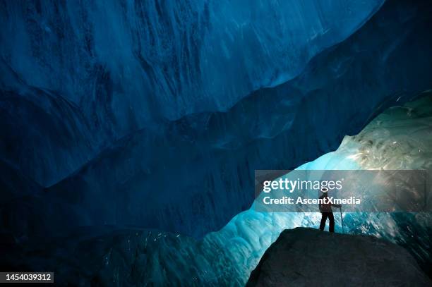 hombre dentro de una cueva de hielo glacial - imponente fotografías e imágenes de stock
